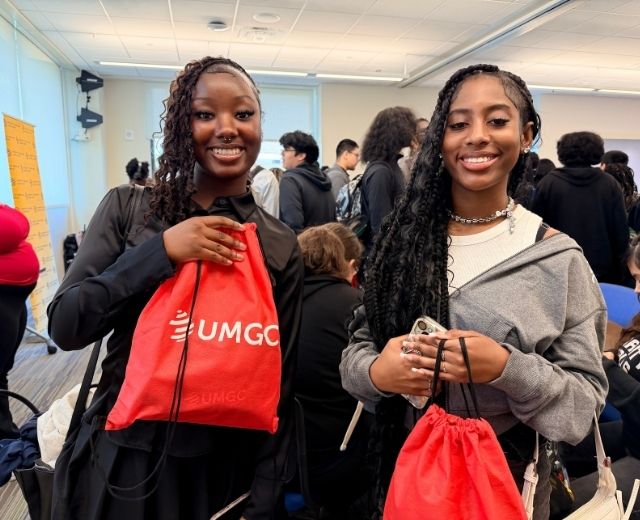 A photo of two Prince George's school system students holding red UMGC 3D Scholar gift bags.