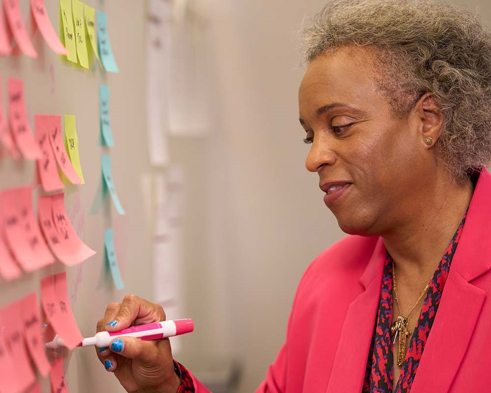 A UMGC Alumni at a project management whiteboard.