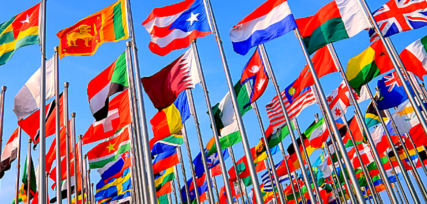 A grouping of country flags from around the world under a blue sky.