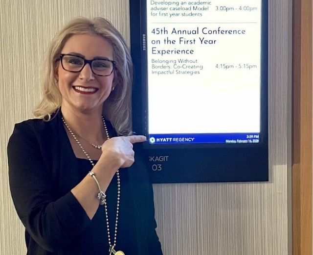 Nancy Trojanowski stands next to a sign touting the 45th conference on the First Year Experience 