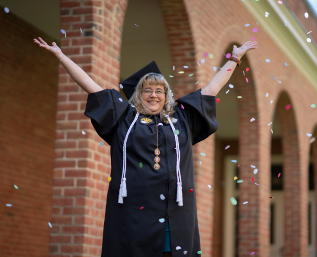 Shelly Kiss throws confetti in the air outside Grad Walk.