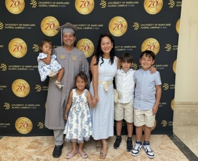 Graduate Rich Gutierrez, his wife and four young children pose and smile at Grad Walk