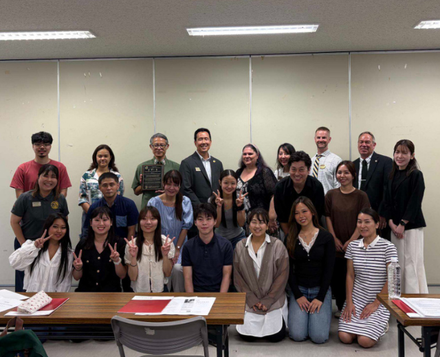 A group of about 22 Bridge Program participants and UMGC and OIHF staff smile in a classroom. 