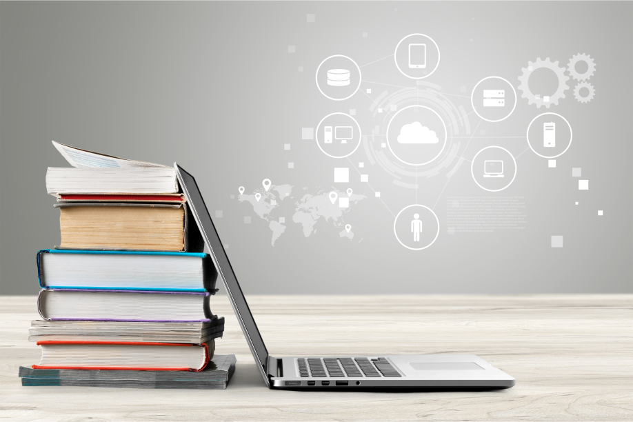 A laptop leaning against a stack of books.