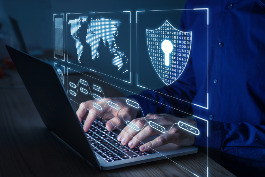A man typing on his laptop with cybersecurity iconography around him.