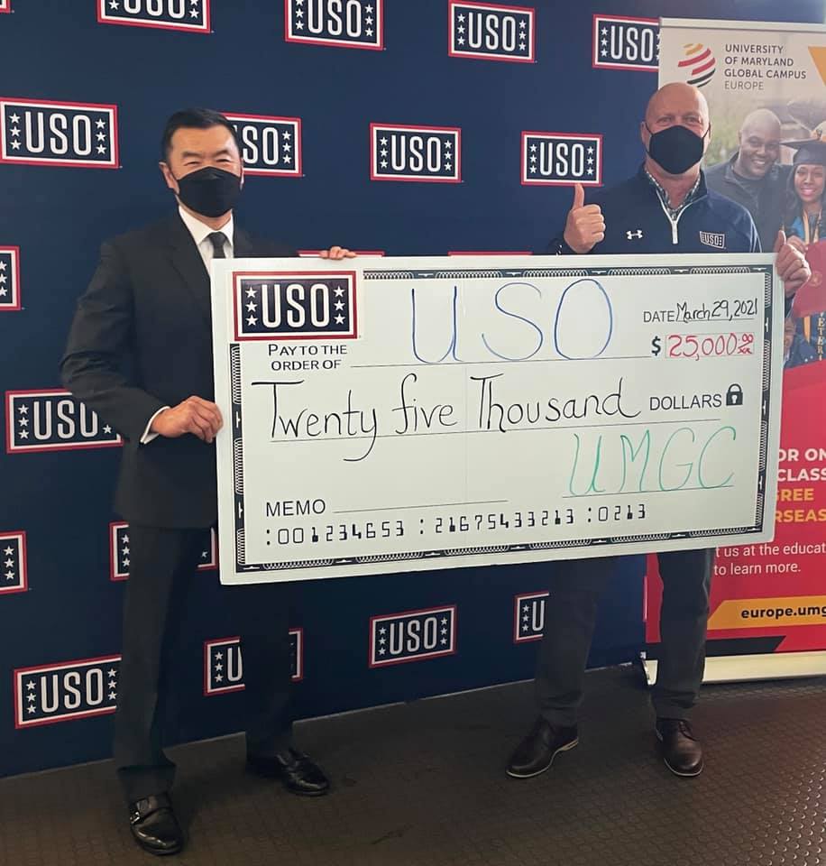 UMGC Europe Leadership holding a large check payable to the USO for $25000.