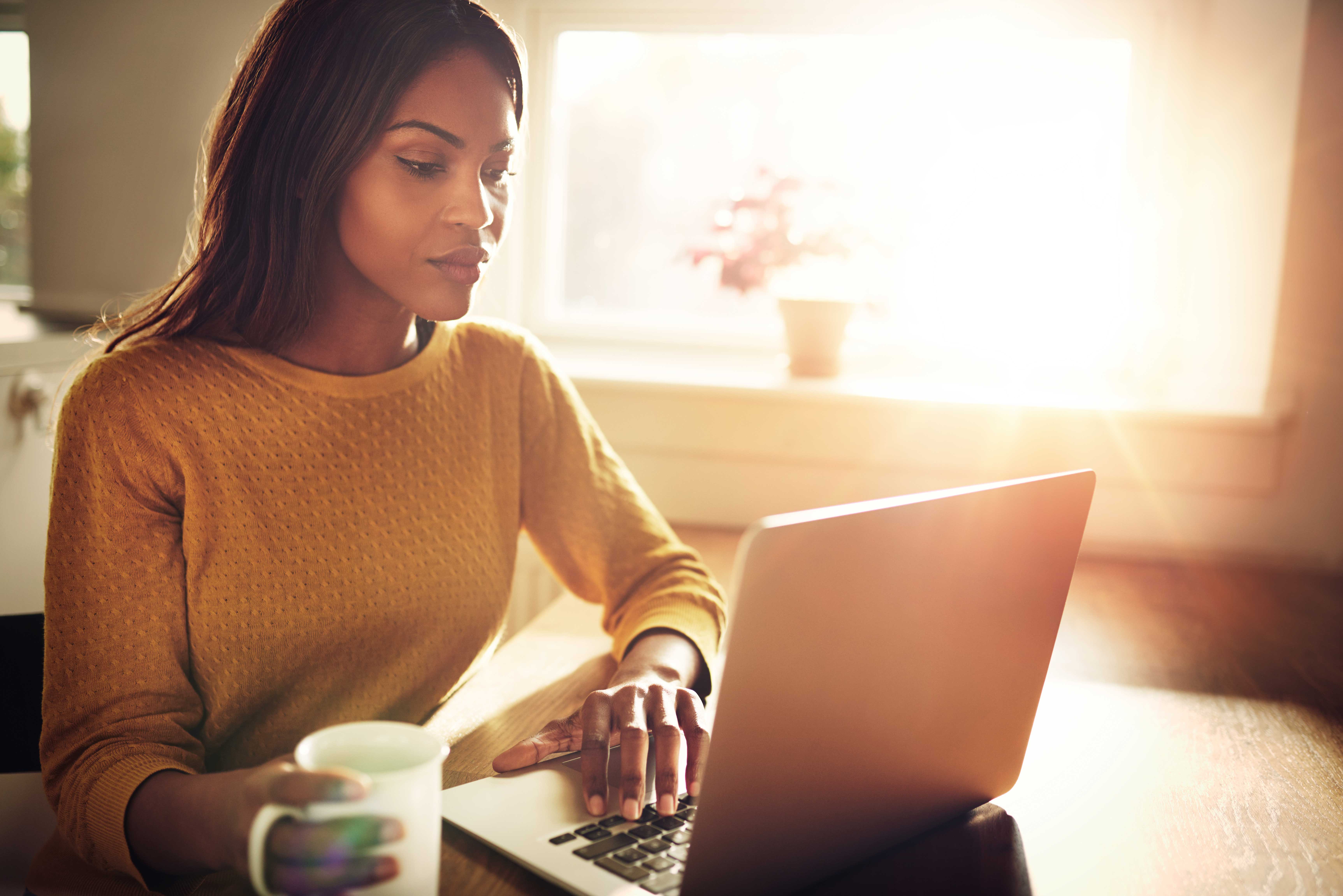 A woman on her laptop in her dining room.