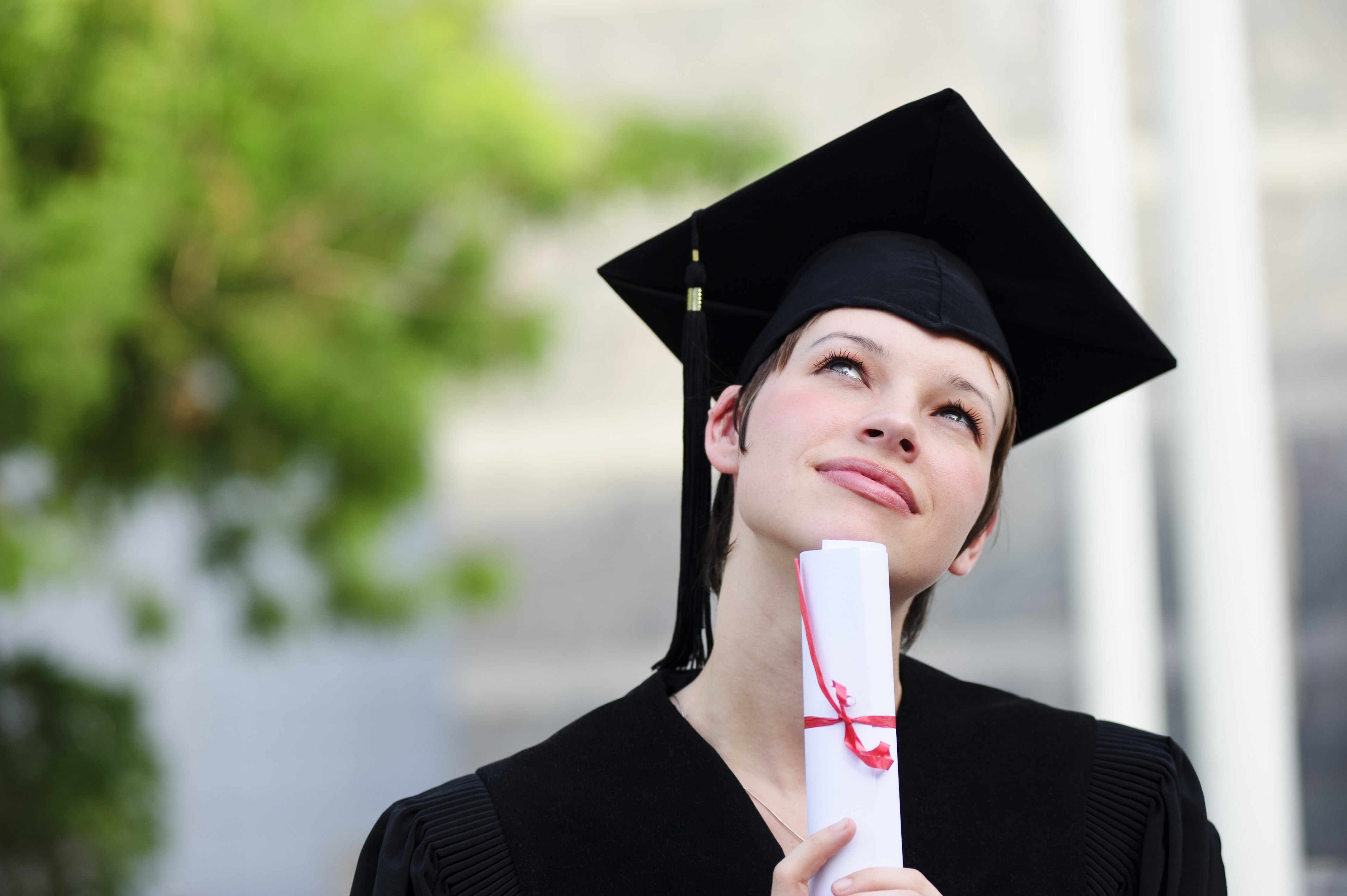 A graduate in her cap and gown thinking.