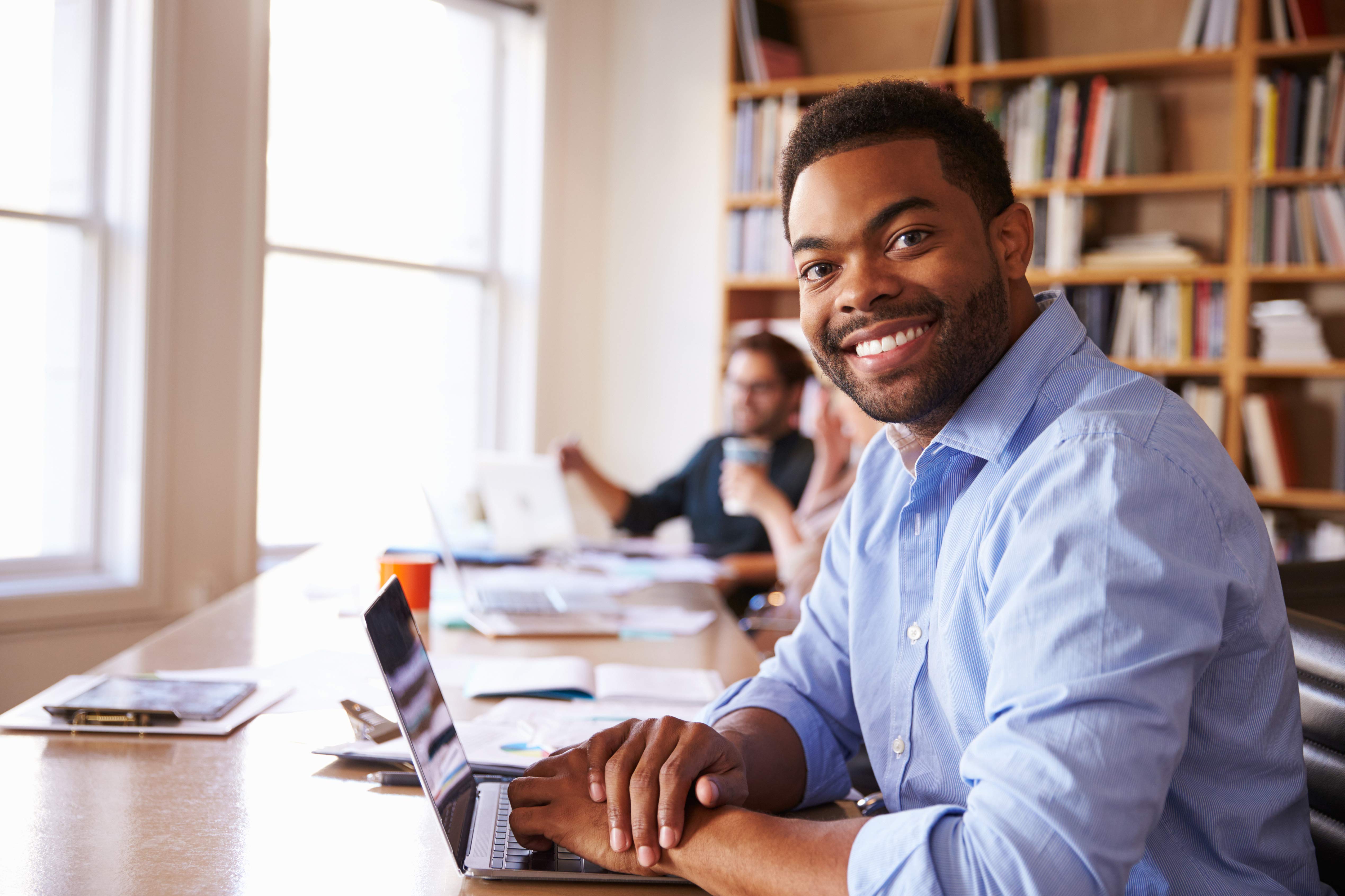 Smiling black male with laptop in library