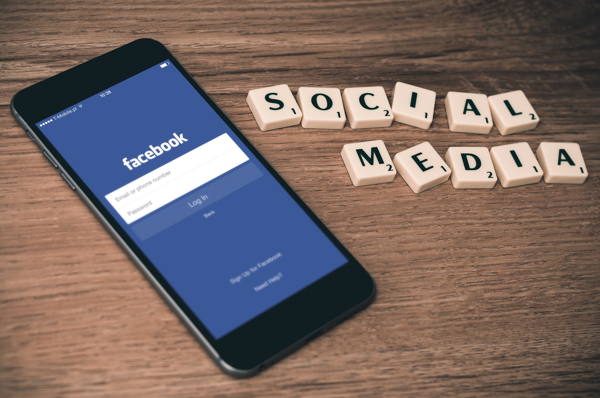 Social Media spelled out in scrabble letters next to smartphone with Facebook app