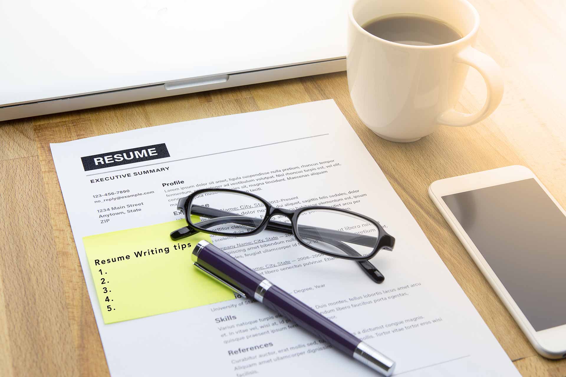 A resume on a desk with coffee and other accoutrements.