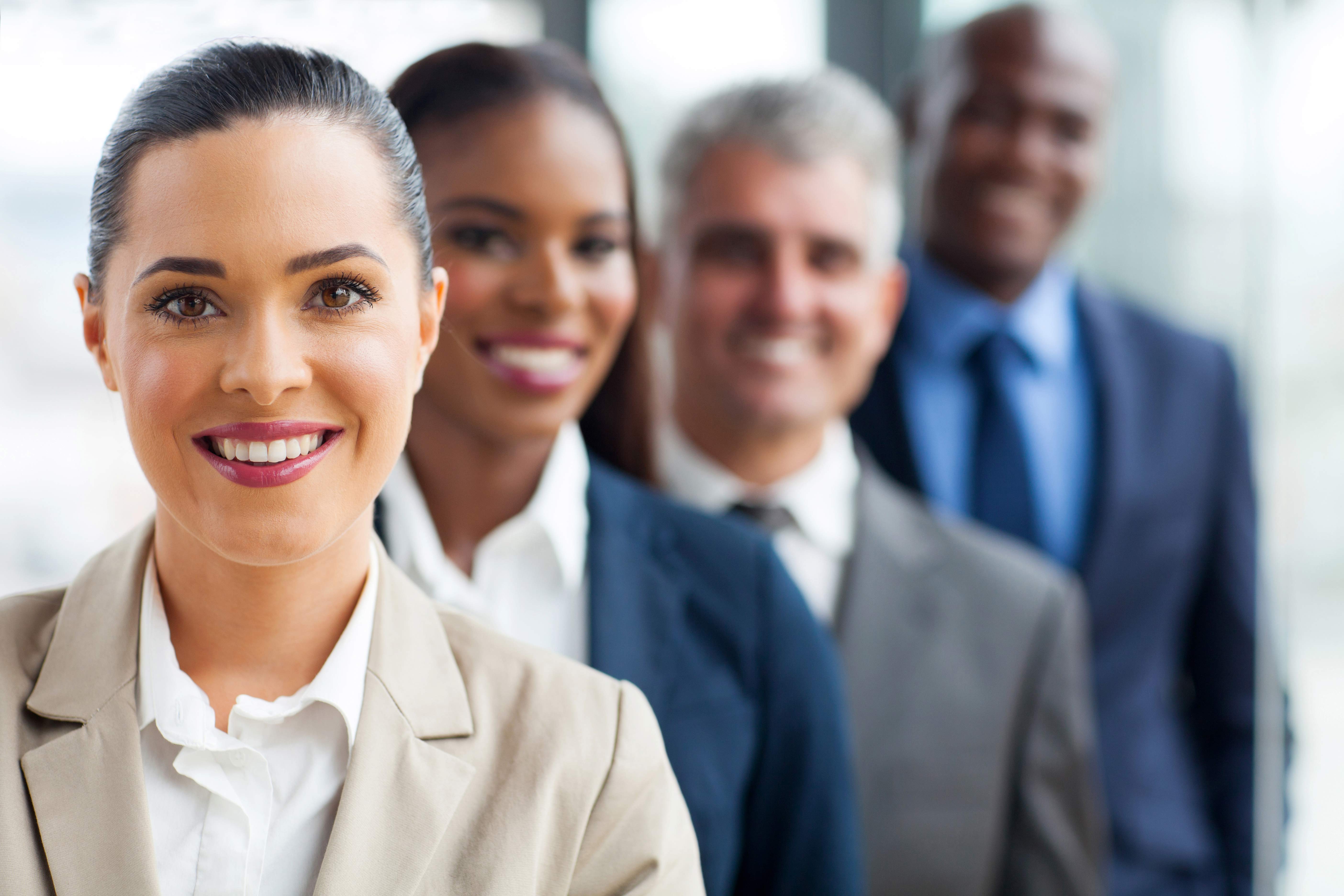 A group of businesspeople smiling and standing in a line.