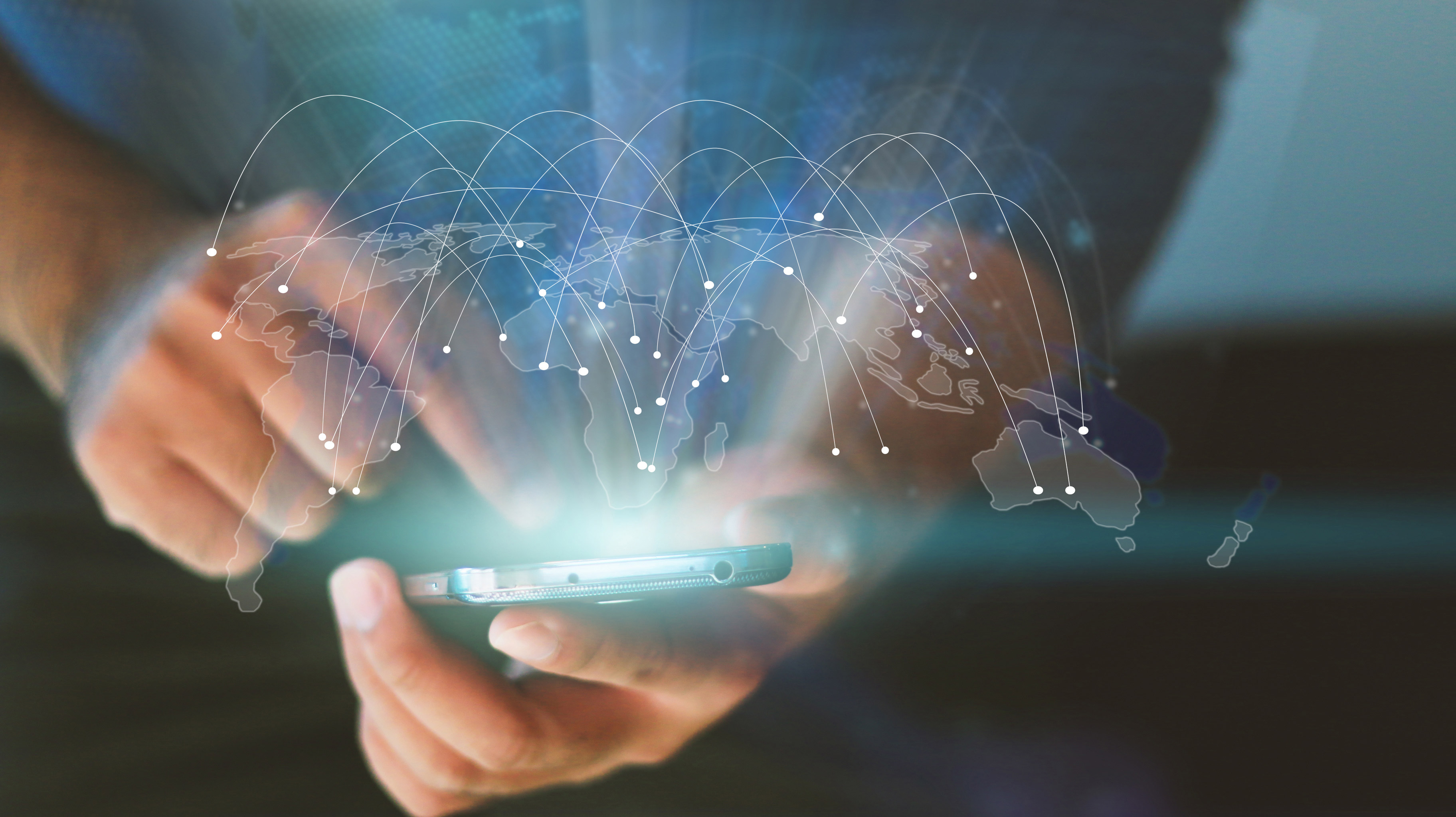 A man touching his mobile phone with a faint overlay of the globe on it.