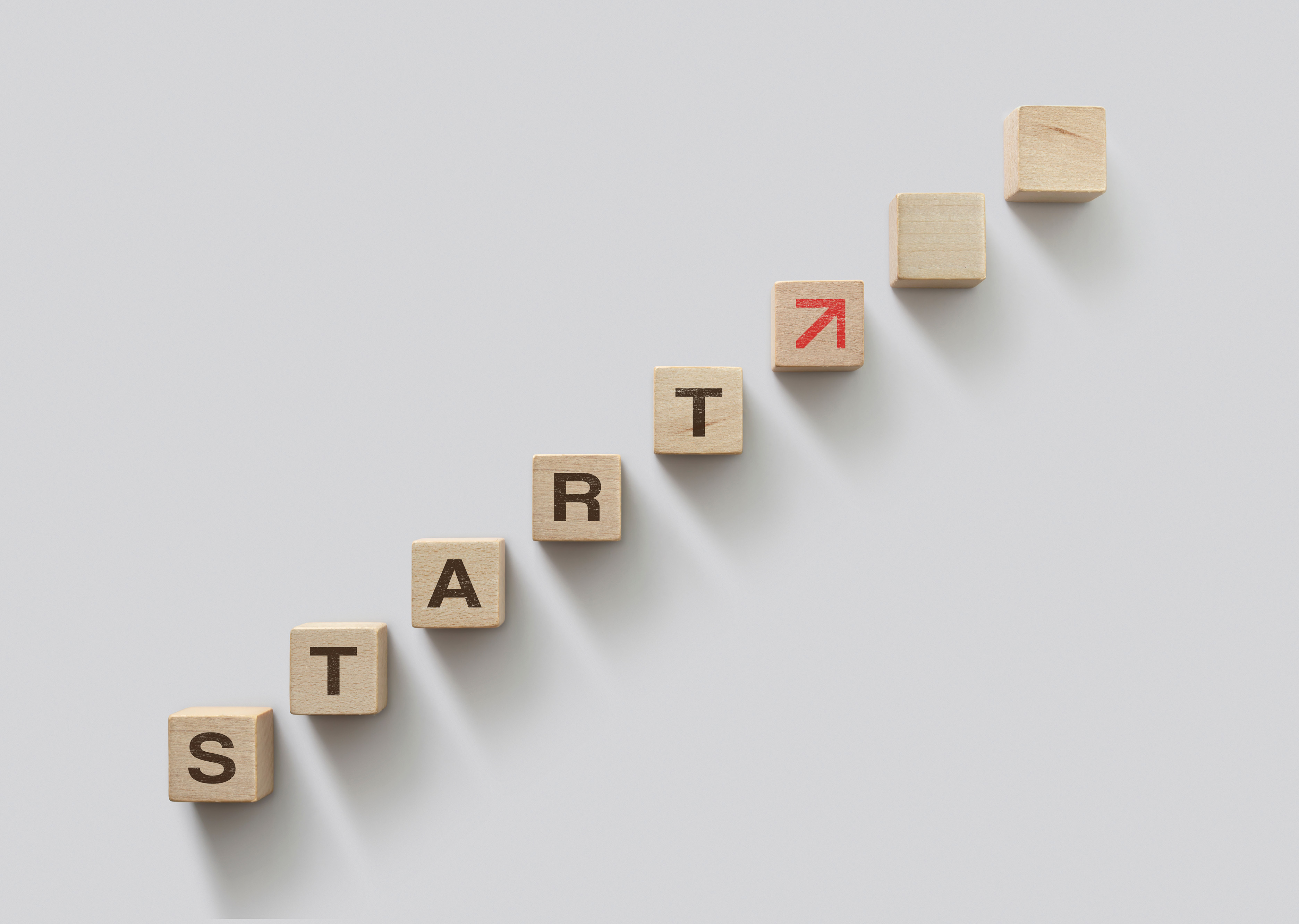 The word 'start' spelled out using wooden blocks with red arrow pointing upwards
