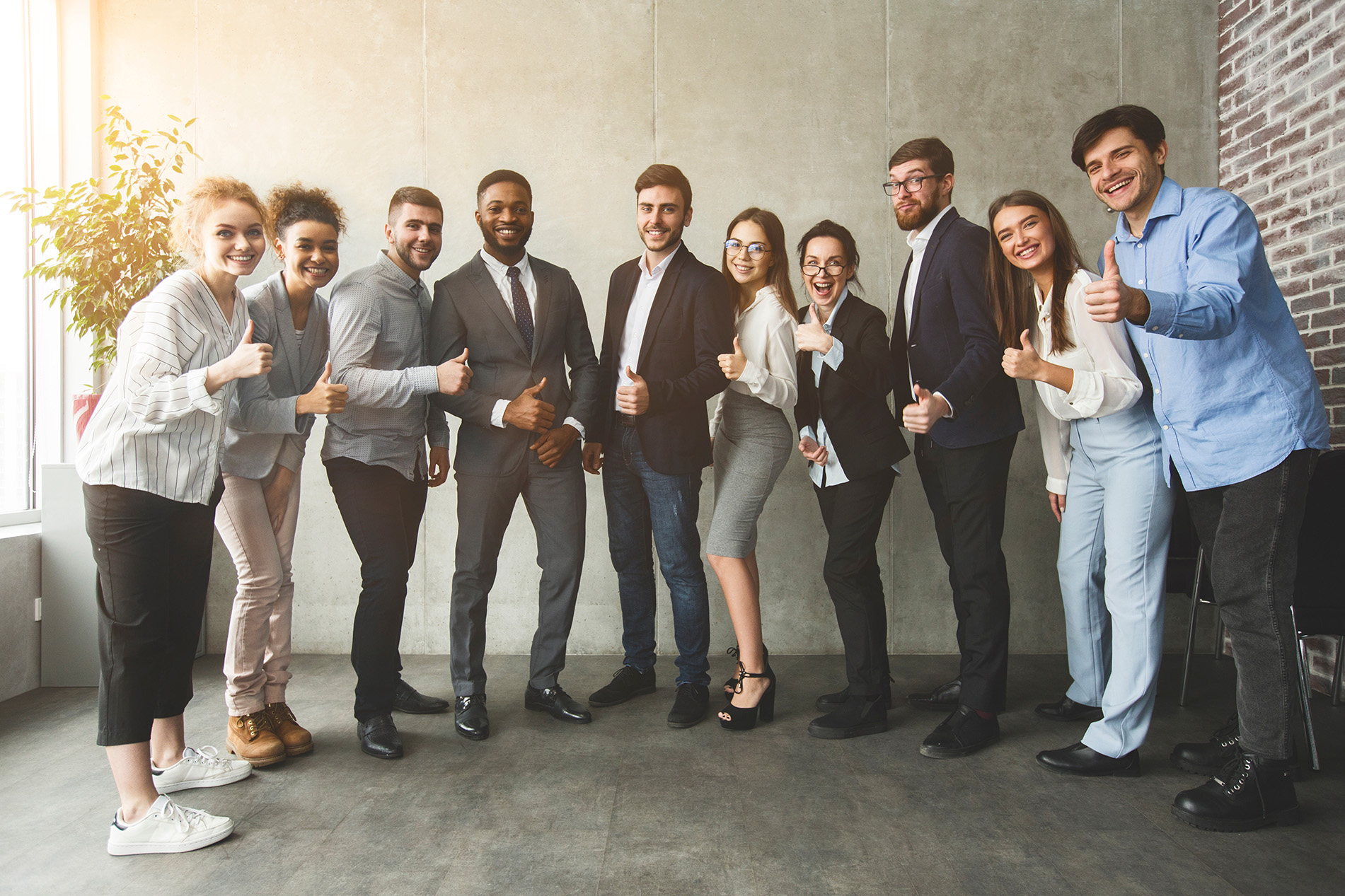 Diverse professionals smiling and giving thumbs up hand sign
