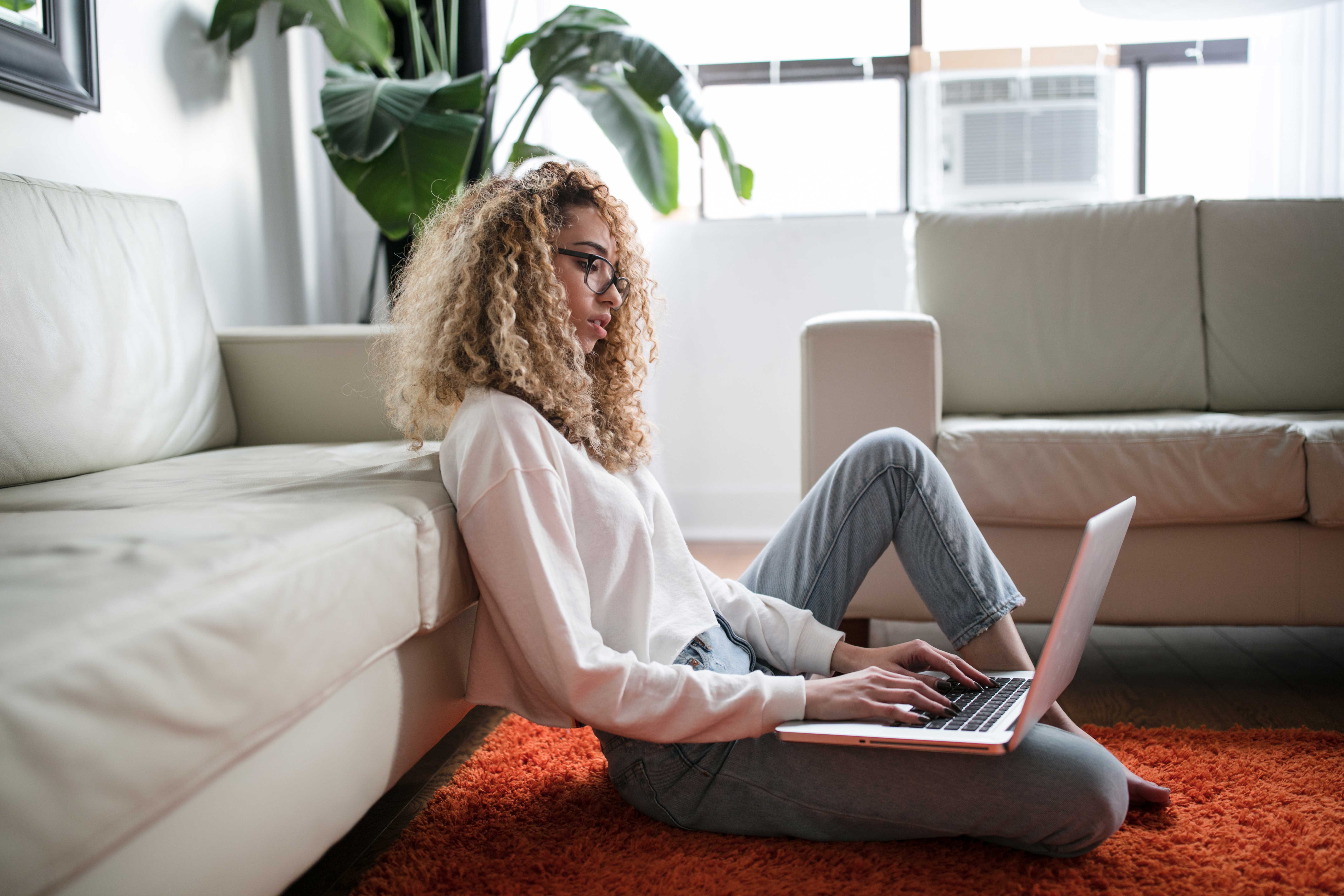 Professional typing on laptop while sitting on floor in living room