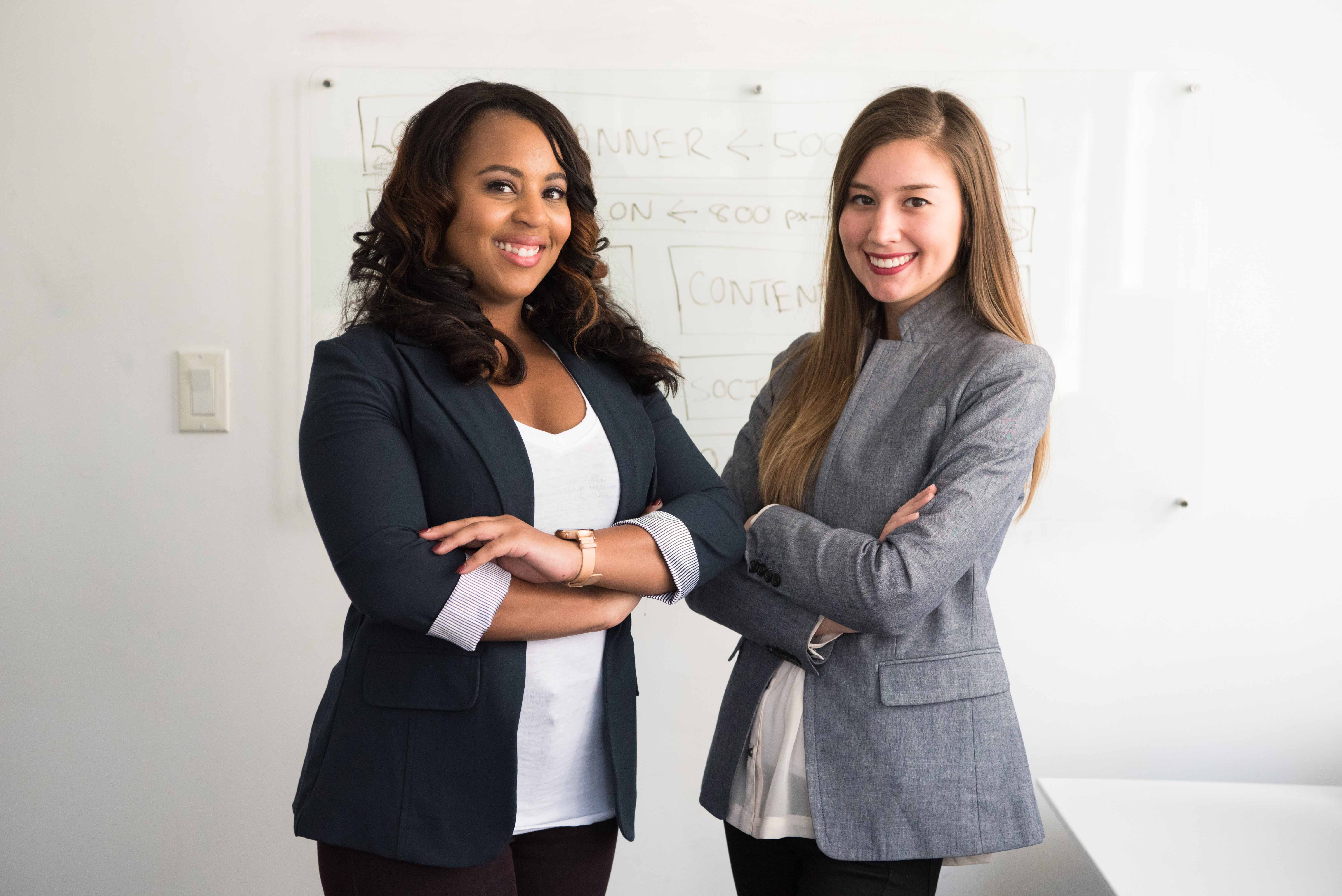 Two businesswomen in front of a whiteboard.