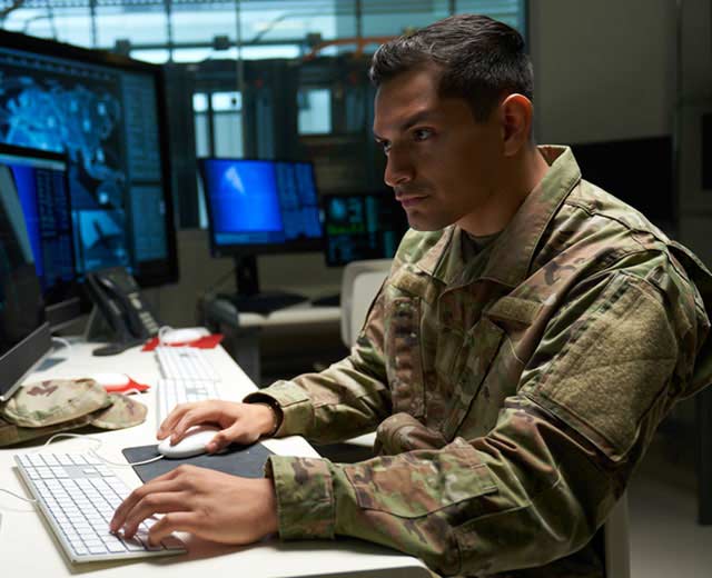 A person in uniform looking at a computer screen.