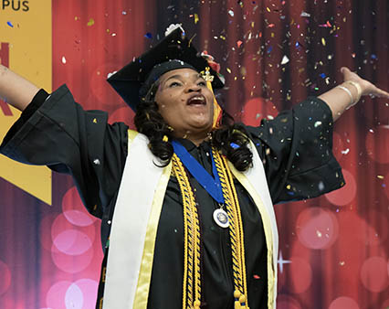 A UMGC graduate throwing confetti at her graduation.