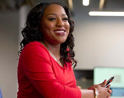 A woman laughing facing right with pen in her hands.