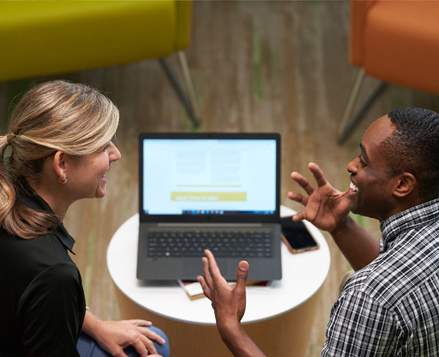 Two people sitting in front of a laptop screen.