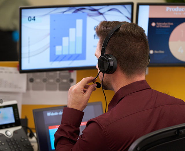 A person wearing a headset in front of a computer monitor.