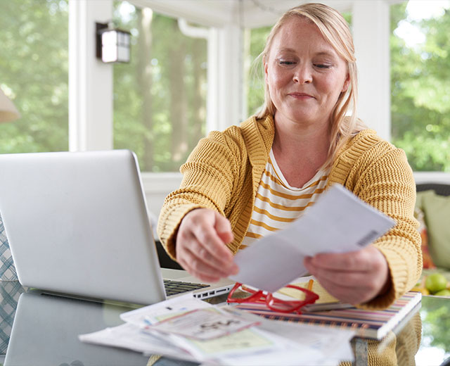 A person holding a piece of paper at a desk.