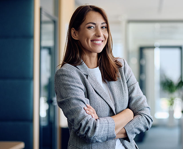 A smiling woman with her arms folded in an office.