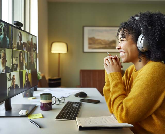 A person on a video conference call smiling and looking at the computer screen.