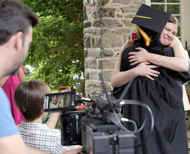 Image of a graduate hugging a family member while being filmed for UMGC's Succeed Again Campaign.