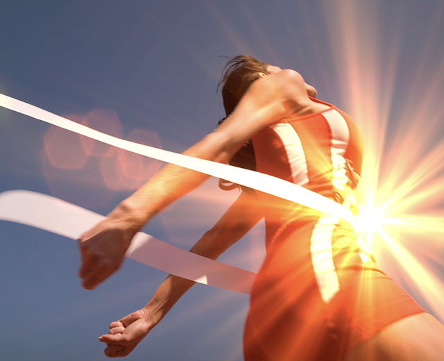 An athlete breaking through finish line tape.