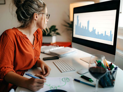 A woman looking at a computer screen and making notes