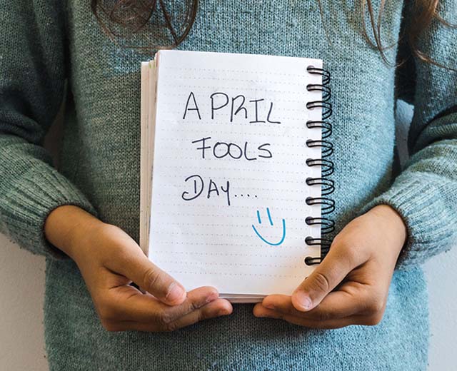 A person holding a notebook with handwriting that says, "April Fools Day."