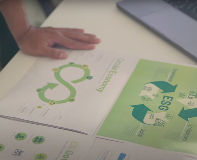 A person's hand resting on a table with ESG and environment-related infographics.