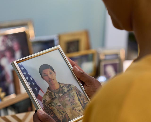 A person holds a picture of a woman in a military uniform.