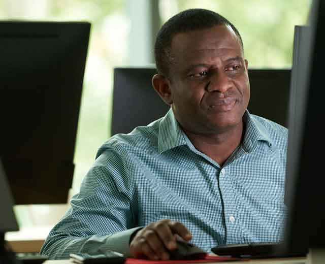 A person looking at a computer monitor and using a mouse.