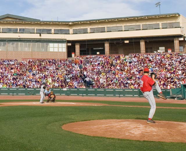 A pitcher throwing a pitch at a crowded baseball game.