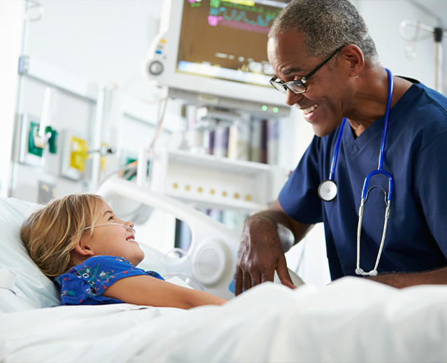 A child and a medical professional smiling in a hospital setting.