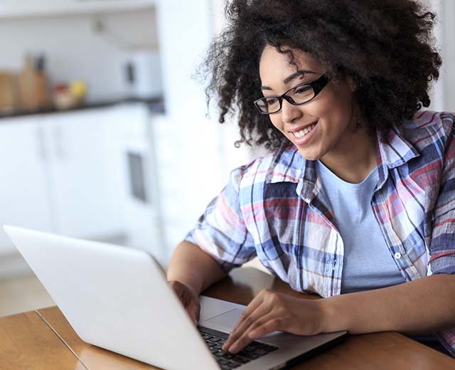 A person typing on a laptop and smiling.