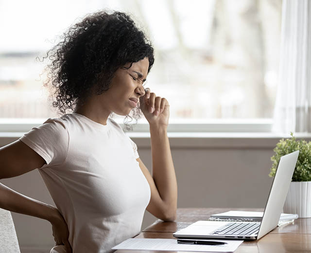 A person grimacing while sitting at a desk.