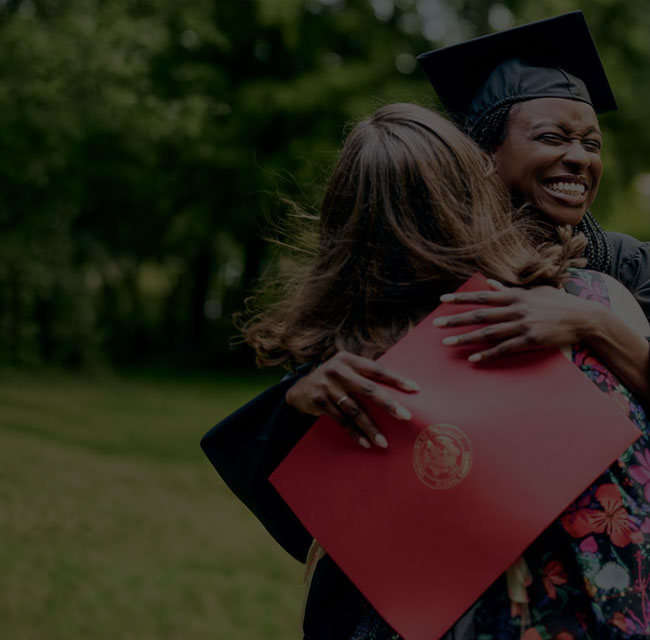 A graduate hugging a friend at Commencement.