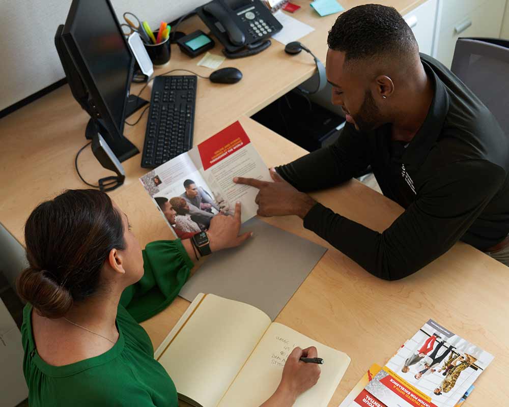 UMGC advisor demonstrating brochure to student