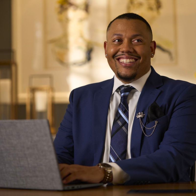 A person typing on a laptop and smiling.