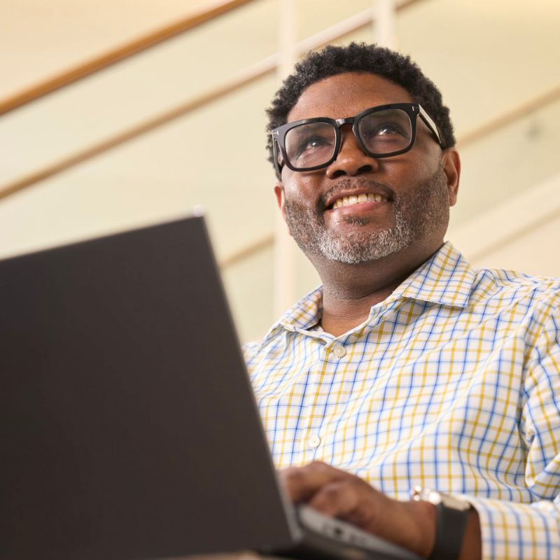 A person typing on a laptop and smiling.