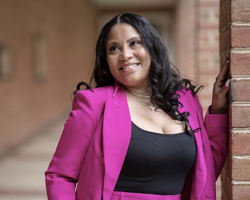 A UMGC graduate in professional clothing smiling in an outdoor location.