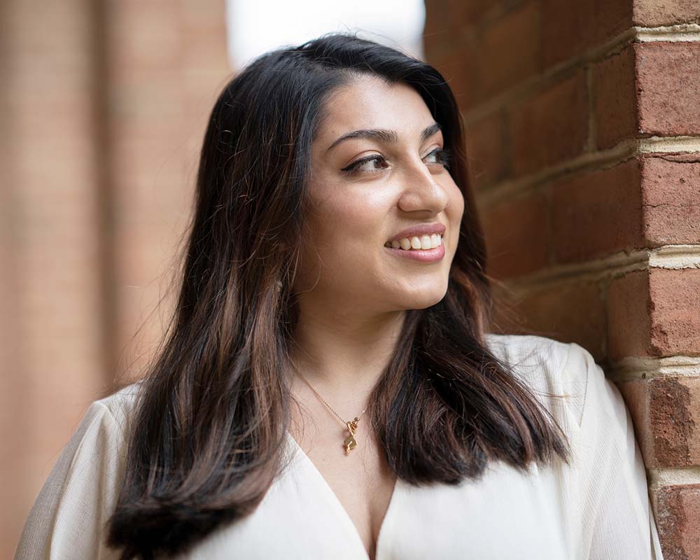 A UMGC graduate in professional clothing smiling in an outdoor location.