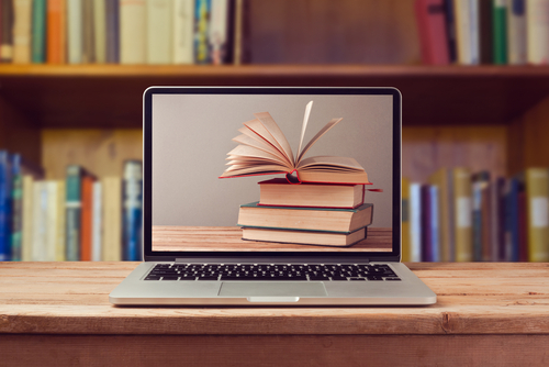 E-book library concept with laptop computer and stack of books on wooden table