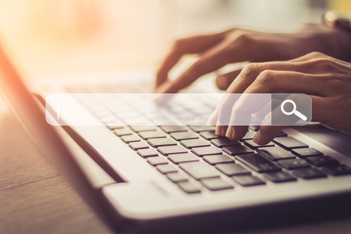 Close up of black man hands typing on a laptop on a desk at home