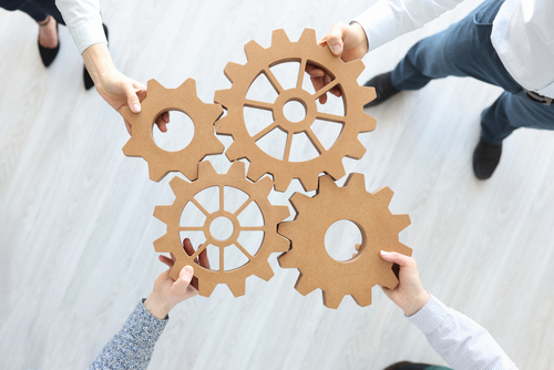Group of business people stacking wooden gears top view. Teamwork concept
