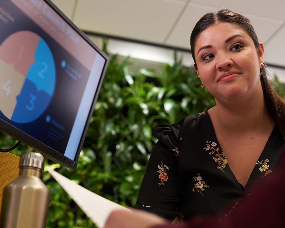 A person smiling in front of a computer screen.